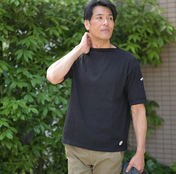 KANELL カネルのメンズの 半袖ニットソー バスクシャツ やサマーセーターとも言う モデルは ISOLDE イソルデ ボートネック で色は黒 ブラック 無地 を一枚でカーキのパンツとコーディネートした写真です