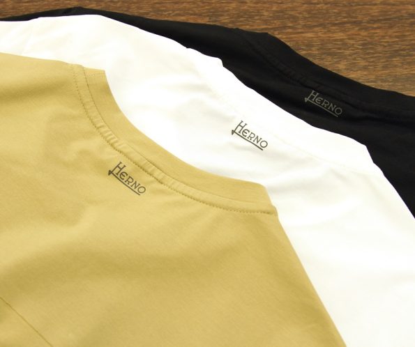 ヘルノ HERNOの変形切り替えデザインの半袖Tシャツの写真です。 メンズ のクルーネックカットソーです。 素材はSUPERFINE COTTON STRETCHと言う、コットンジャージーで、レギュラーフィットです。 色はキャメルとホワイトと、ブラック3枚の写真です。