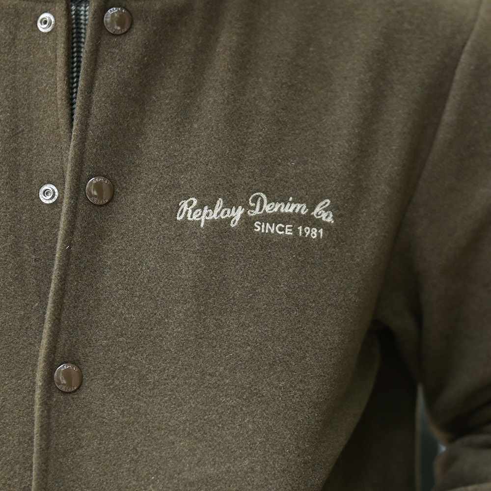 REPLAY カーキ系ウール混メルトンスタジャンの胸元Replay Denim Co.筆記体刺繍と刻印スナップボタンのディテール